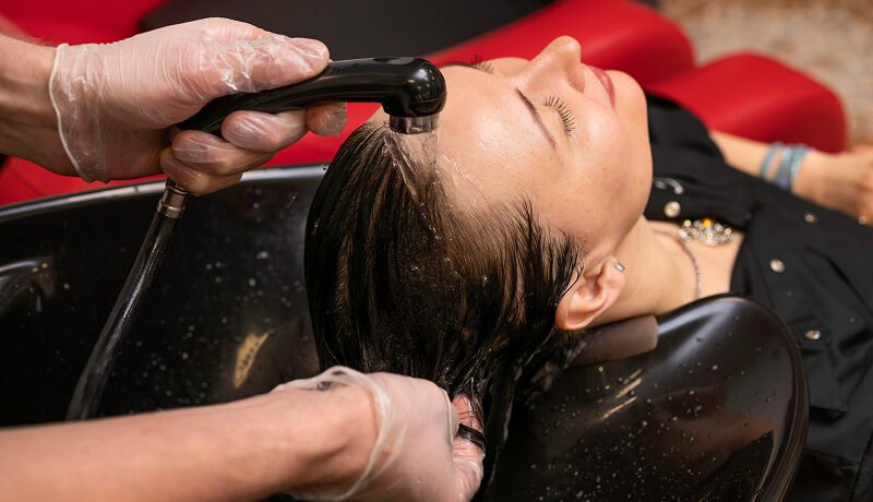 Woman receiving a professional scalp wash for hair loss treatment.