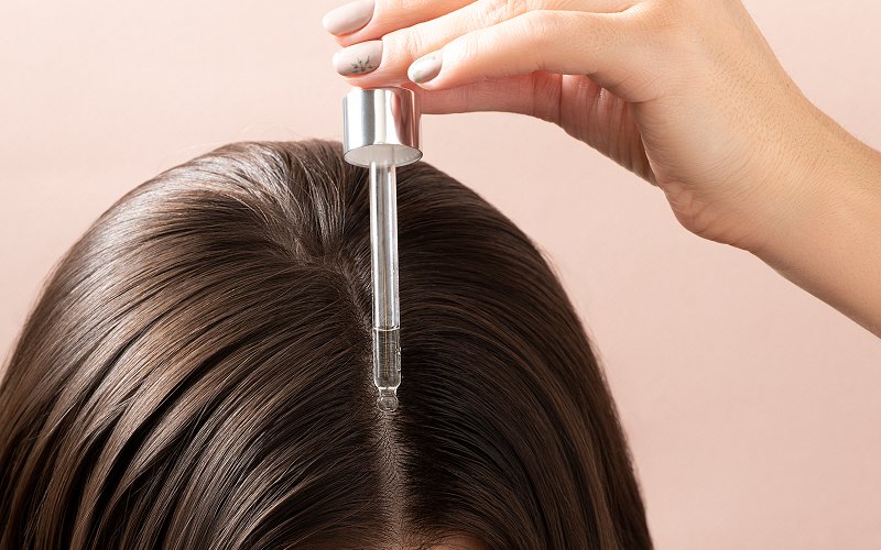 Applying hair loss treatment serum directly to the scalp.