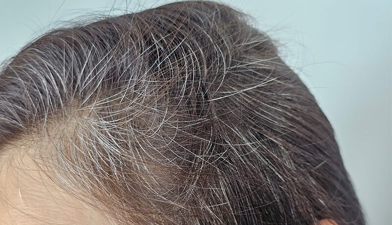 Close-up of silver grey hair roots along natural scalp parting.
