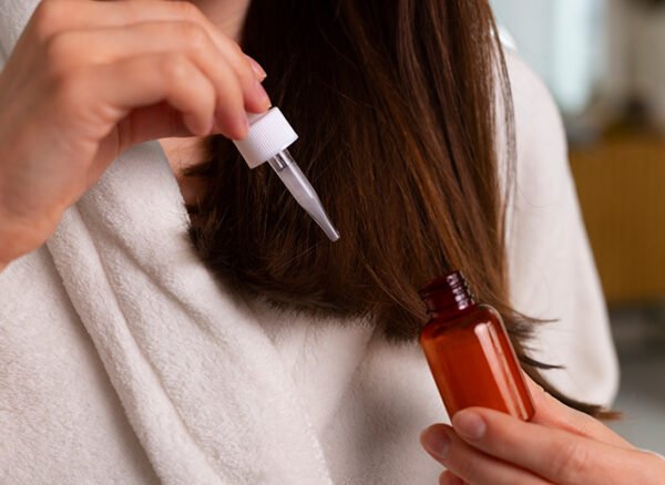 Woman applying oil to hair strands with a dropper. Woman applying oil to hair strands with a dropper.