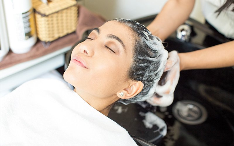 Woman receiving a deep cleansing shampoo treatment at a salon.