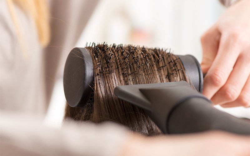 Close-up of blow drying hair with round brush styling.