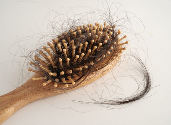 Wooden hairbrush showing signs of excessive daily hair loss.