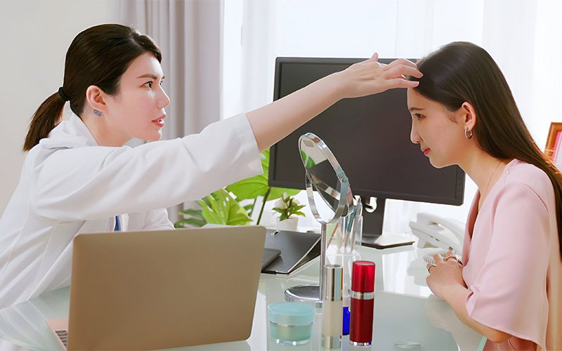 Hair specialist examining patient scalp for oily scalp hair loss.