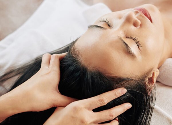 Woman receiving relaxing head massage to improve scalp microcirculation. Woman receiving relaxing head massage to improve scalp microcirculation.
