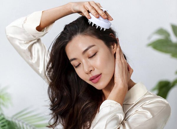 Woman using a scalp massager brush for gentle exfoliation. Woman using a scalp massager brush for gentle exfoliation.