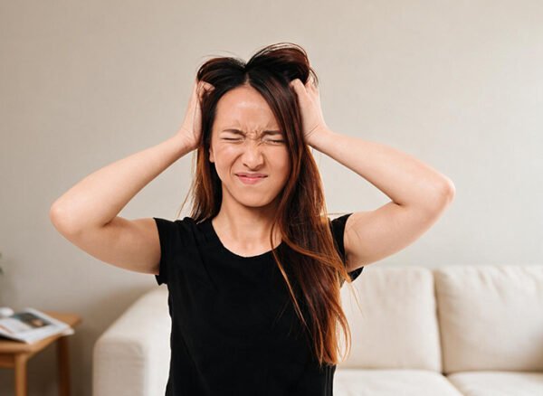 Woman scratching her itchy head due to sensitive scalp irritation.